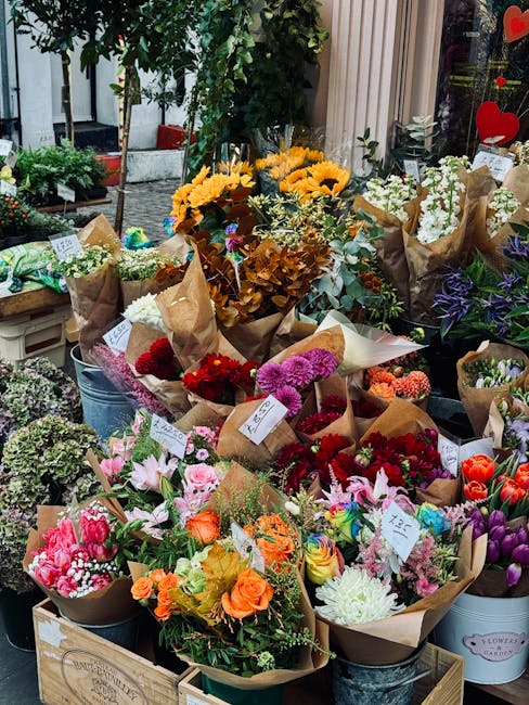 A vibrant display at Bethnal Green Florist showcasing an assortment of freshly cut flowers arranged in bouquets and buckets. The arrangements include bright yellow sunflowers, pink and white lilies, d
